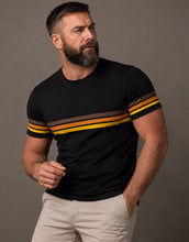 Man wearing a black t-shirt with yellow and brown stripes on a gray background