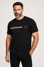 Man wearing a black t-shirt with a rainbow and logo design on a plain background