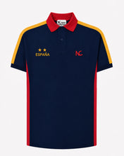 A navy blue short-sleeve polo shirt with red and yellow accents, featuring 'ESPAÑA' with two stars on the left chest and a red 'NC' logo on the right chest, displayed on a light gray background.