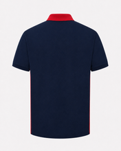 A navy blue short-sleeve polo shirt shown from the back, featuring a contrasting red collar and red side stripes, set against a plain light gray background.