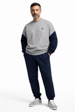 Man wearing a gray and navy color-blocked sweater with matching pants on a white background