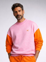 Man wearing a pink and orange sweatshirt with a logo on a plain background