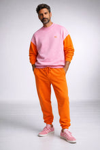 Man wearing a pink and orange sweatshirt with matching pants on a white background